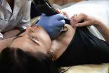 woman in black shirt being tattooed in chest